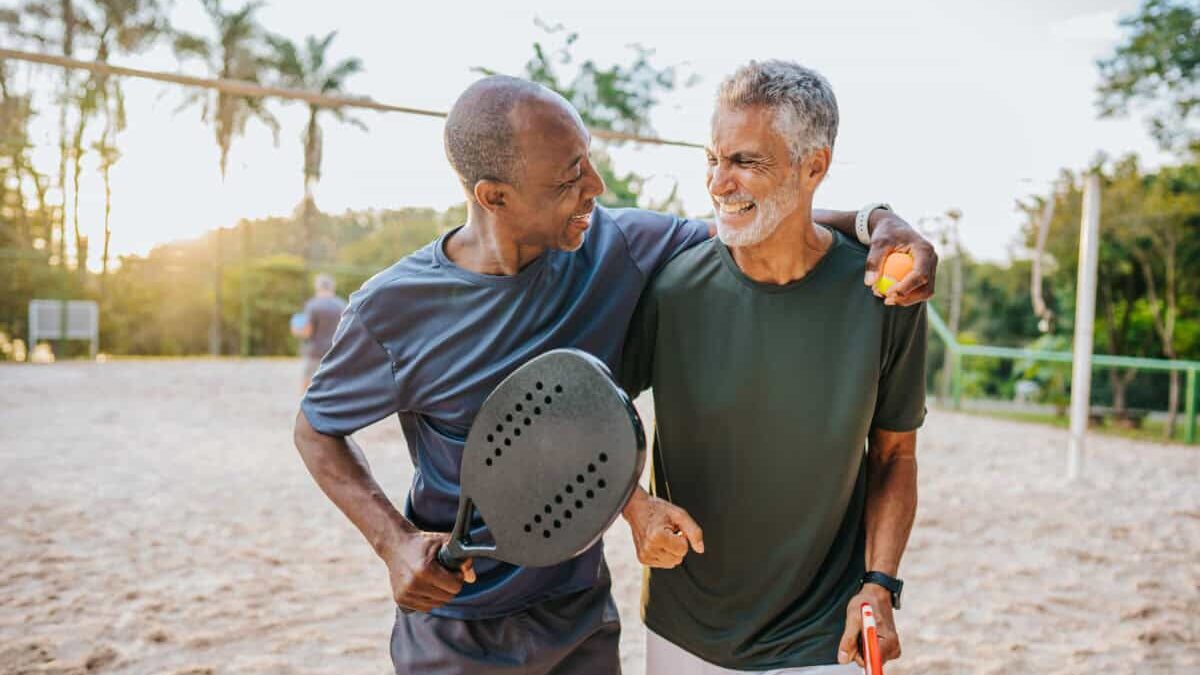 Two senior friends playing beat tennis on sand tennis court