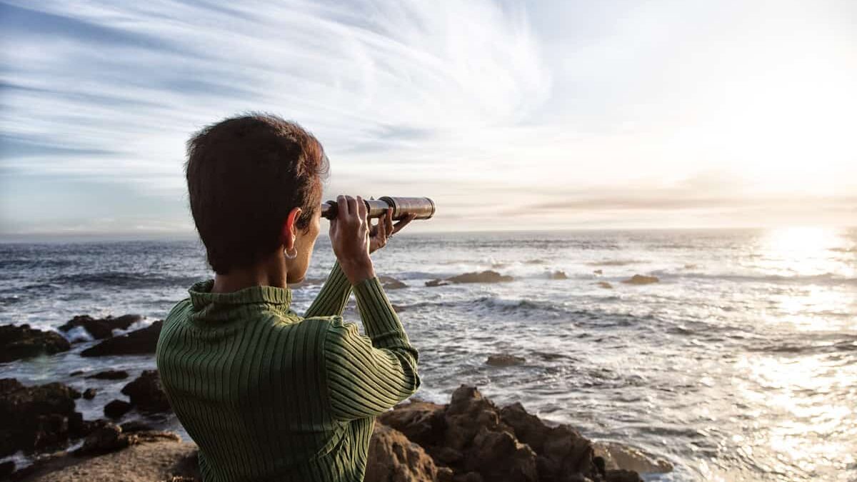 person with spyglass looks at ocean horizon